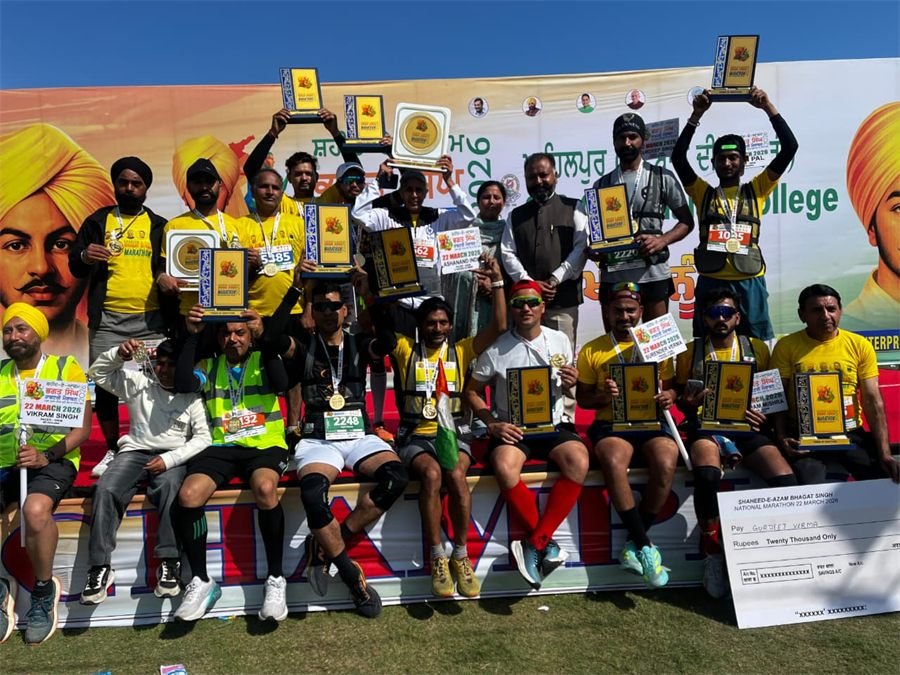 Marathon winners holding their trophies and medals in front of the Shaheed-e-Azam Bhagat Singh National Marathon backdrop